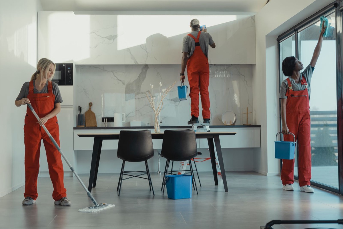 Cleaning team mopping floors and wiping glass together